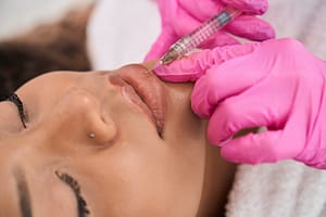 Female undergoes an injection lip correction procedure in cosmetology clinic
