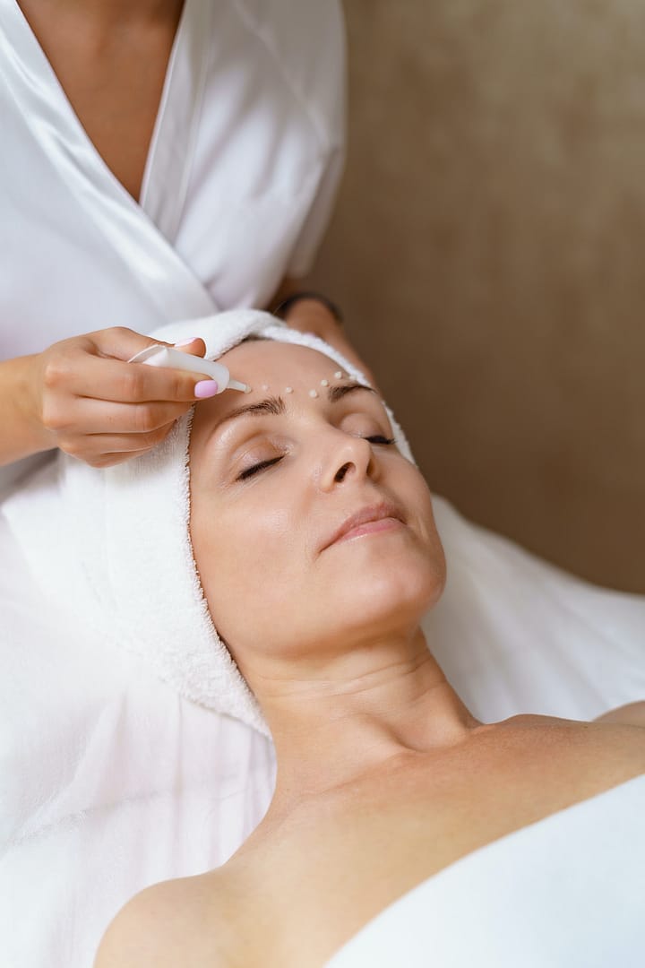 Cosmetologist applying cream on face