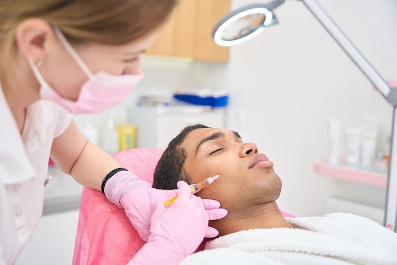 Beauty salon customer receiving cheek filler injection